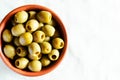 Pickled pitted green olives in a ceramic bowl on a light background. Healthy food concept. Rustic style. Top view. Royalty Free Stock Photo