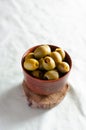 Pickled pitted green olives in a ceramic bowl on a saw cut tree on a light background. The concept of vegetarian food. Royalty Free Stock Photo