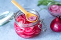 Pickled red onion rings on a wooden spoon on a glass jar. Appetizer, condiment or topping. Healthy fermented food.