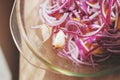 Pickled red onion, roughly chopped, with lemon and garlic in a glass dish, top view