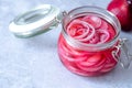 Pickled red onions in glass jar on a gray background. Appetizer, condiment or topping. Healthy fermented food.