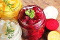 Pickled red, white, orange beet in glass jars. Variety pickles on rustic background