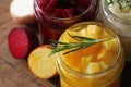 Pickled red, white, orange beet in glass jars. Variety pickles on rustic background