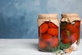 Pickled tomatoes in glass jars and products on white wooden table against blue background Royalty Free Stock Photo