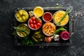 Pickled vegetables and mushrooms in glass jars in Wooden box on black stone background. Royalty Free Stock Photo