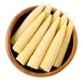 Pickled whole baby corn in wooden bowl over white