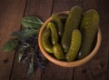 Pickles in a clay bowl on a dark rustic background with lettuce leaves