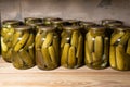 Pickles or salted cucumbers in glasses on a wooden shelf in cellar