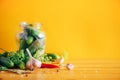 Pickling cucumbers in cans. Ingredients for marinated gherkins, glass jar, garlic, dill, salt, pepper on yellow Royalty Free Stock Photo