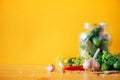 Pickling cucumbers in cans. Ingredients for marinated gherkins, glass jar, garlic, dill, salt, pepper on yellow Royalty Free Stock Photo