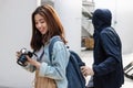 Pickpocket thief stealing wallet from backpack of tourist Asian girl