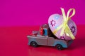 Pickup toy carrying one decorated easter egg on a pink background Royalty Free Stock Photo