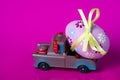 Pickup toy carrying one decorated easter egg on a pink background Royalty Free Stock Photo