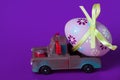 Pickup toy carrying one decorated easter egg on a violet background Royalty Free Stock Photo