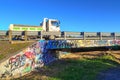 Pickup truck speeds by on a graffiti covered bridge