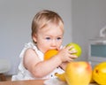 Picky eater blond blue-eyed toddler holding and biting fruits. Healthy eating habits. Children snack