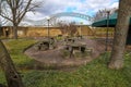 A Picnic Area With Circular Stone Tables And Stone Cylinders For Seats Surrounded By Lush Green Grass And Bare Winter Trees