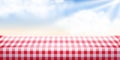 Picnic background. Red checkered tablecloth, blue sky, clouds. Empty space food table. Tabletop advertisement backdrop Royalty Free Stock Photo