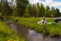 A picnic on the bank of a mountain river with green grass and yellow flowers against the background of coniferous trees and a blue Royalty Free Stock Photo