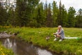 A picnic on the bank of a mountain river with green grass and yellow flowers against the background of coniferous trees and a blue Royalty Free Stock Photo