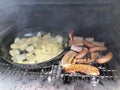 Barbequing pork meat and sausages with dollar chips potatoes close up