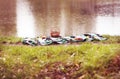 Picnic basket with apples, yellow autumn leaves on a blanket in green grass near the water.