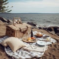 Picnic basket, blanket, pillows, food and dishes in a beautiful landscape on the beach near the sea. Royalty Free Stock Photo