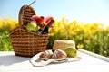 Picnic basket with bottle of wine and food on wooden table in lily field Royalty Free Stock Photo