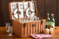 picnic basket filled with picnic essentials and sitting on wooden table