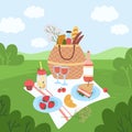 Picnic basket in park. Serving in nature. Romantic lunch in forest clearing. Eating outdoor. Tablecloth with food on