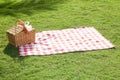 Picnic basket with a red and white tablecloth on the green lawn Royalty Free Stock Photo