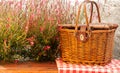 Picnic basket on the table with red flowers