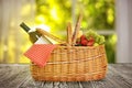 Picnic basket with wine and fruits on wooden table indoors Royalty Free Stock Photo