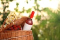 Picnic basket with wine, strawberries and flowers on blurred background