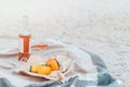 Picnic on the beach with persimmons, almond and bottle of rose wine on beige blanket