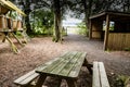 Picnic bench set in a wooded area surrounded by shrubs, trees and other wooden structures