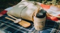 A picnic blanket with a bottle of water and wooden spoons. AI generative image.