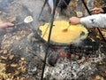 A picnic with a company by the fire. Cooking omelet from eggs on a fire. Chicken eggs on fire in the forest