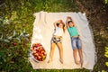 Children having a little picnic in summer garten with apples, spreading on white blanket.
