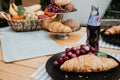 Picnic with croissants, fruits, lemonade, Coca Cola and Pepsi on a wooden table at the camping