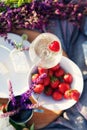 Picnic in grass, cheese, strawberries, wildflowers, glass of champagne on wooden board