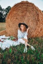 Picnic at the hayloft. Woman in cowboy hat sitting near a straw bale. Summer, beauty, fashion, glamour, lifestyle concept. Royalty Free Stock Photo