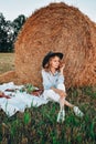 Picnic at the hayloft. Woman in cowboy hat sitting near a straw bale. Summer, beauty, fashion, glamour, lifestyle concept. Royalty Free Stock Photo