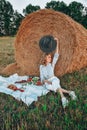 Picnic at the hayloft. Woman in cowboy hat sitting near a straw bale. Summer, beauty, fashion, glamour, lifestyle concept. Royalty Free Stock Photo