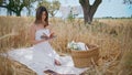 Picnic model riffling novel pages in summer field. Woman reading book at nature Royalty Free Stock Photo