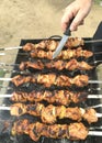 Barbecue, kebab on a grat. A man with a knife tastes barbecue readiness.Appetizing meat is fried in nature.
