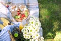 Picnic in the park on the green grass, on a sunny summer day. Flowers, basket, wine in glasses and a blanket. Copy space. Flat lay Royalty Free Stock Photo