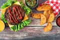 Picnic scene with hamburger and potato wedges over dark wood Royalty Free Stock Photo