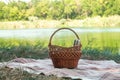 Picnic set, metal Cutlery, thermos, plates tea cups. brown plaid and napkin from the lake in the background. green grass. Sunny su