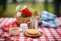 a picnic setting with a basket, red checkered cloth, and biscuits with gravy